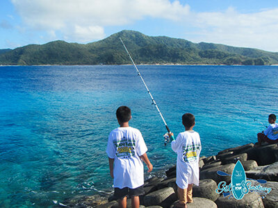 Children fishing from a rocky shore
