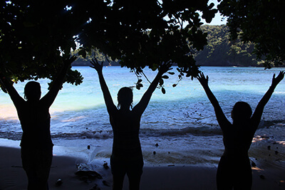 silhouettes of three women standing on a beach with their arms raised